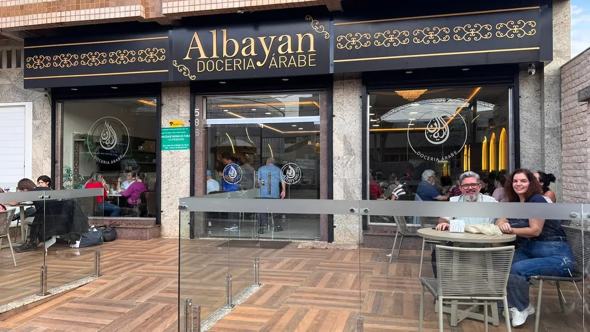Interior da doceria árabe Albayan em Foz do Iguaçu com clientes na vitrine de doces