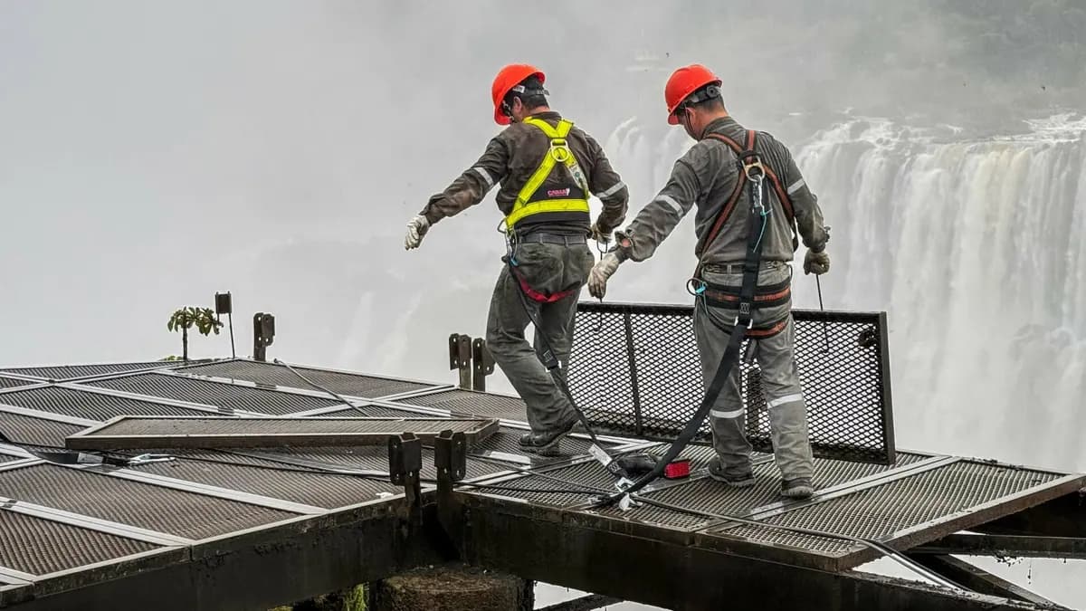 Trabalhadores com capacete e cinto de segurança removem o piso da passarela da Garganta do Diabo, com a queda ao fundo