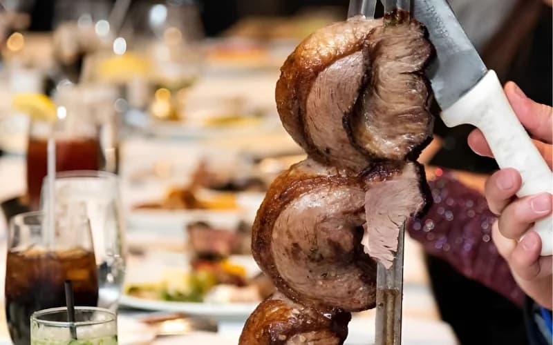 Corte de picanha sendo servido diretamente na mesa durante o jantar no Rafain Churrascaria Show