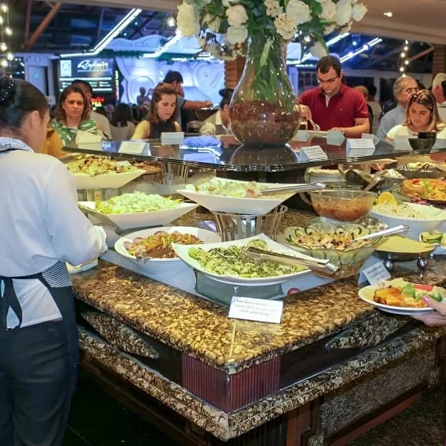 Buffet de saladas e pratos quentes do Rafain Churrascaria Show com visitantes se servindo