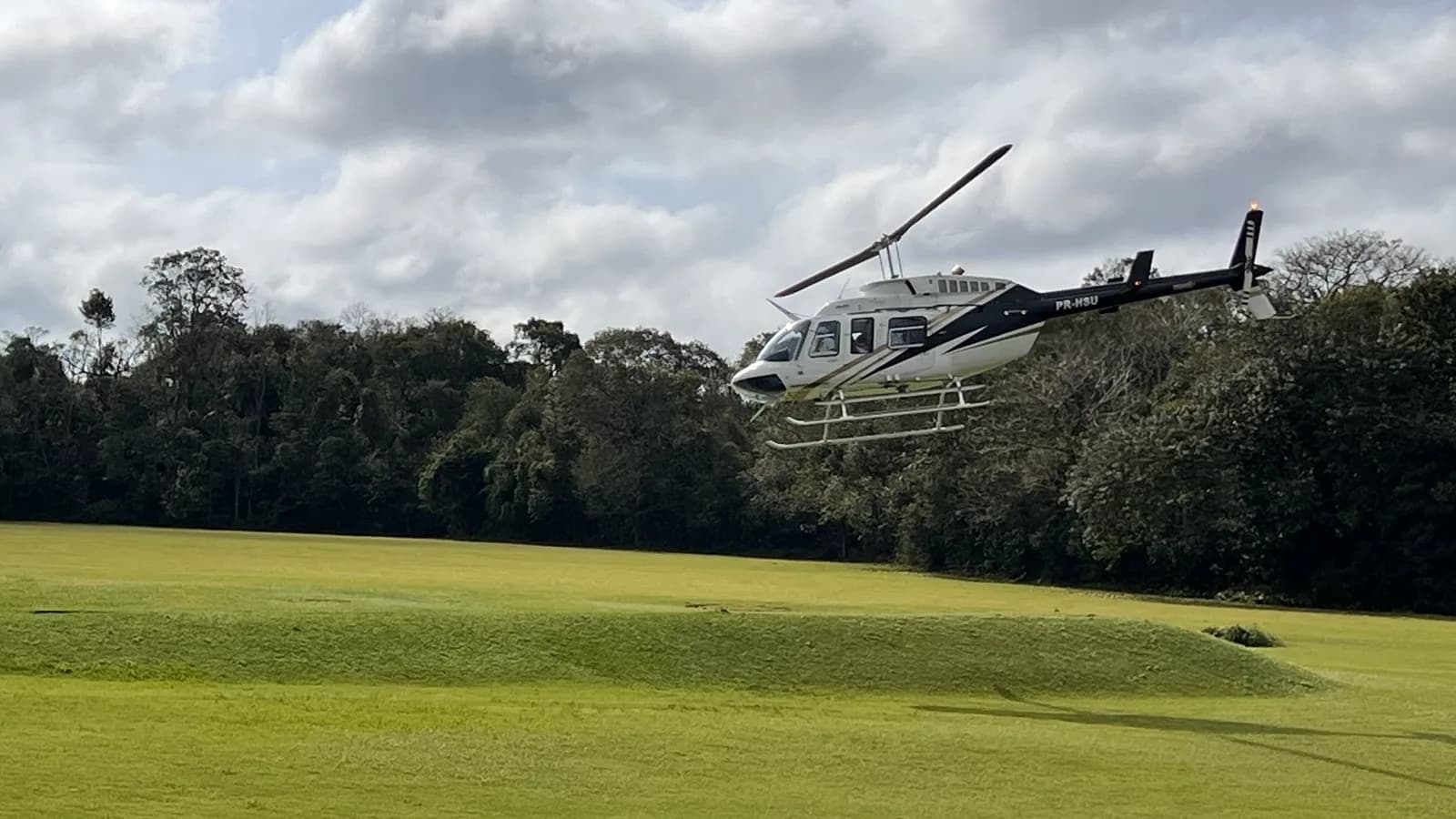 Helicóptero da Helisul decolando baixo sobre as árvores do heliponto em Foz do Iguaçu