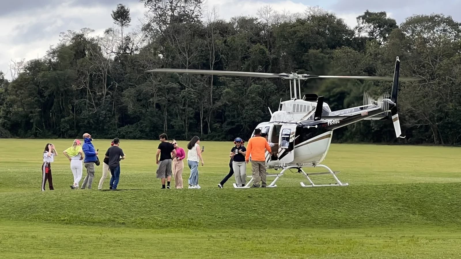 Grupo de clientes caminhando no gramado do heliponto para embarcar no helicóptero da Helisul